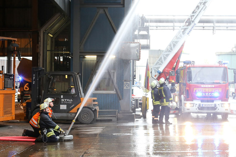Die Werkfeuerwehr kühlt die Fassade während die Freiwellige Feuerwehr der Mittelstadt Völklingen (rechts im Bild) die Drehleiter ausfährt. (Foto: Saarstahl AG)