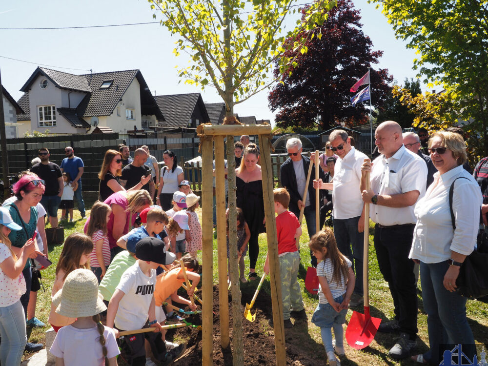 Oberbürgermeister Stephan Tautz (4. v. re.), der Lauterbacher Ortsvorsteher Erik Roskothen (3. v. re.) und Bürgermeister Christof Sellen (2. v. re.) mit zahlreichen Kindern und Besucherinnen und Besuchern bei der Pflanzung der Zitterpappel in Lauterbach. Bild: Stadt Völklingen