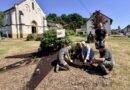 Oberbürgermeister Stephan Tautz (Mitte) und VHS-Direktor Lars Hüsslein (stehend) mit Mitarbeitern der Beruf Saar gGmbH (ZBB) und der VHS Völklingen am Beet vor der Wendalinus-Kapelle. Bild: Stadt Völklingen