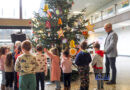 Die Kinder der Kita Lauterbach präsentieren Oberbürgermeister Stephan Tautz (re.) den geschmückten Tannenbaum im Foyer des Neuen Rathauses in Völklingen.  Bild: Stadt Völklingen