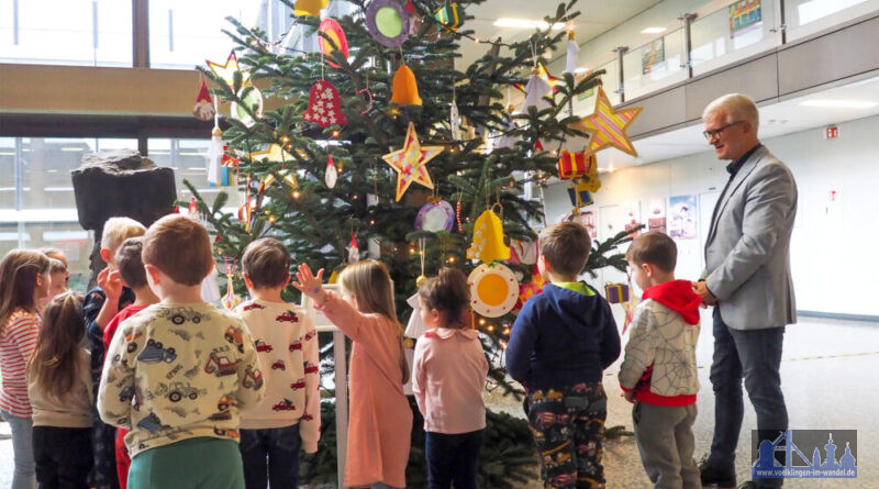 Die Kinder der Kita Lauterbach präsentieren Oberbürgermeister Stephan Tautz (re.) den geschmückten Tannenbaum im Foyer des Neuen Rathauses in Völklingen.  Bild: Stadt Völklingen