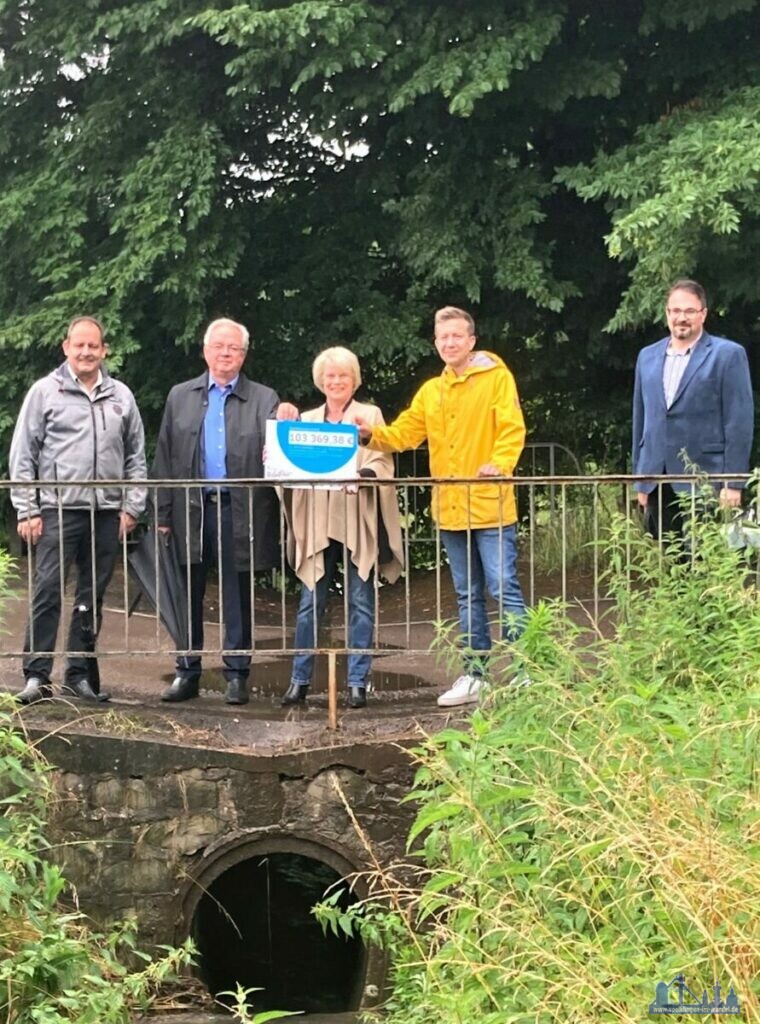 Bild: V.l.n.r.: Reiner Zimmer (SPD-Landtagsabgeordneter), Ortsvorsteher Dieter Peters, Christiane Blatt, Sebastian Thul und Volker Müller (städt. Fachdienst Technische Dienste/Straßen-, Brücken- und Kanalbau) bei der Bescheidübergabe am Lauterbach. (Stadt Völklingen, S.Feß)