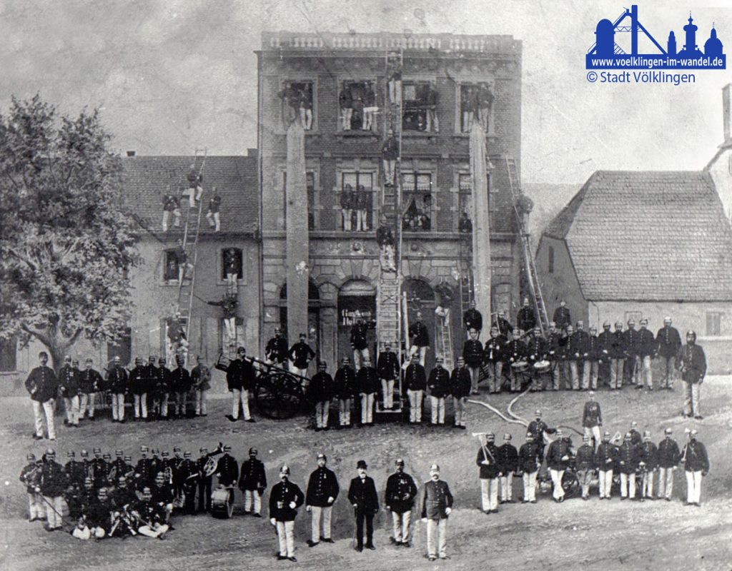  Die Feuerwehr Völklingen bei einer Übung in der damaligen Wilhemstraße 7 im Jahre 1885 (Varietehaus [Variete=Theater] Jakobs Nikolaus) - eine Besonderheit: Diese Fotomontage zeigt als einziges bekannte Bild den damaligen Bürgermeister Carl Stürmer - im Vordergrund in der Mitte.