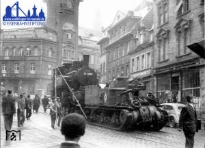 Der Kampfpanzer des Typs M3 Lee/Grand passiert mit der Saarbrücker 91 1819 im Schlepptau das Rathaus Völklingens © Eisenbahnstiftung